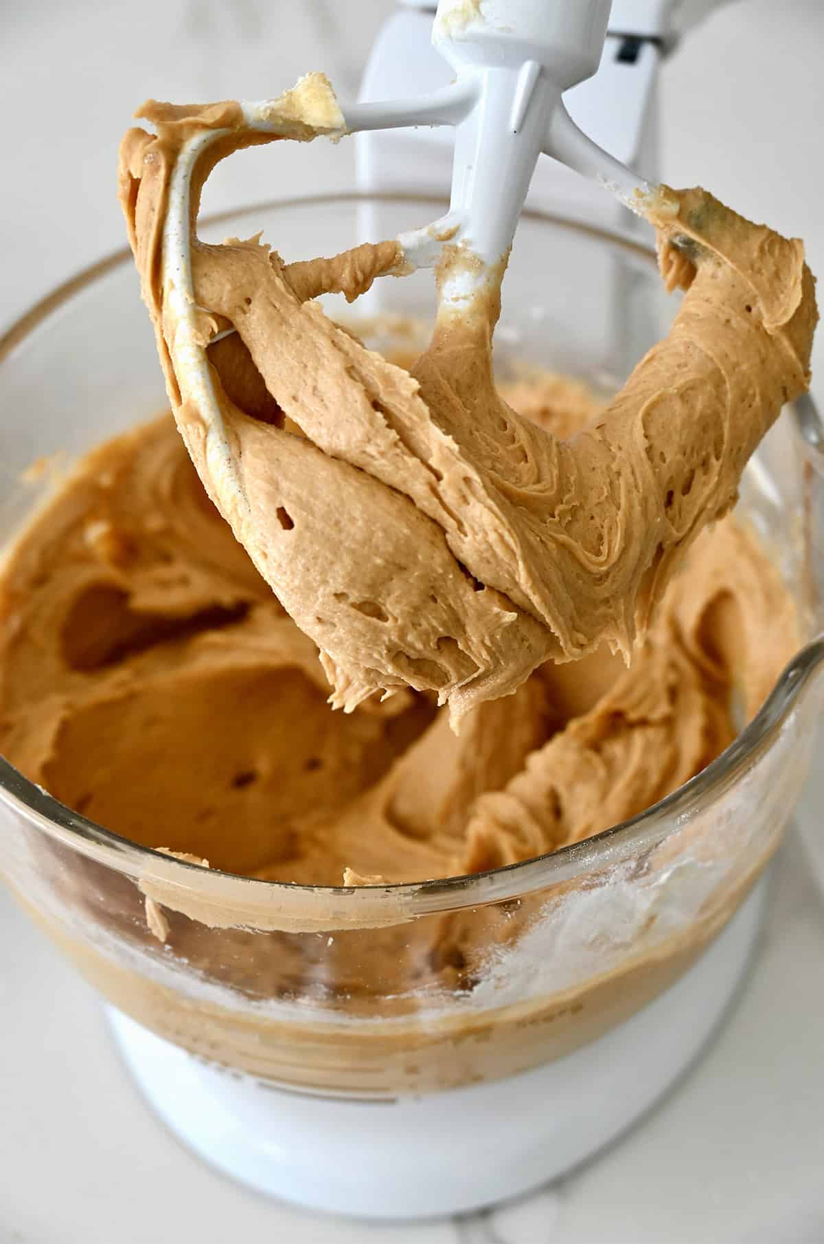 Creamy peanut butter mixed with butter and vanilla extract in a stand mixer.