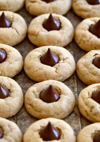 Three rows of peanut butter blossoms on a dark wood surface.