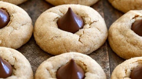 Three rows of peanut butter blossoms on a dark wood surface.