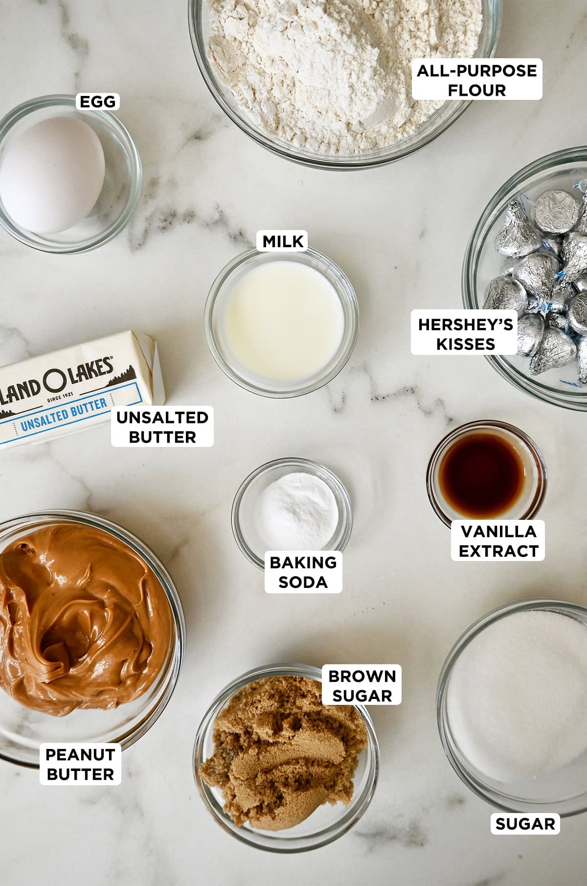 The ingredients needed to make peanut butter blossoms in various sizes of glass bowls.