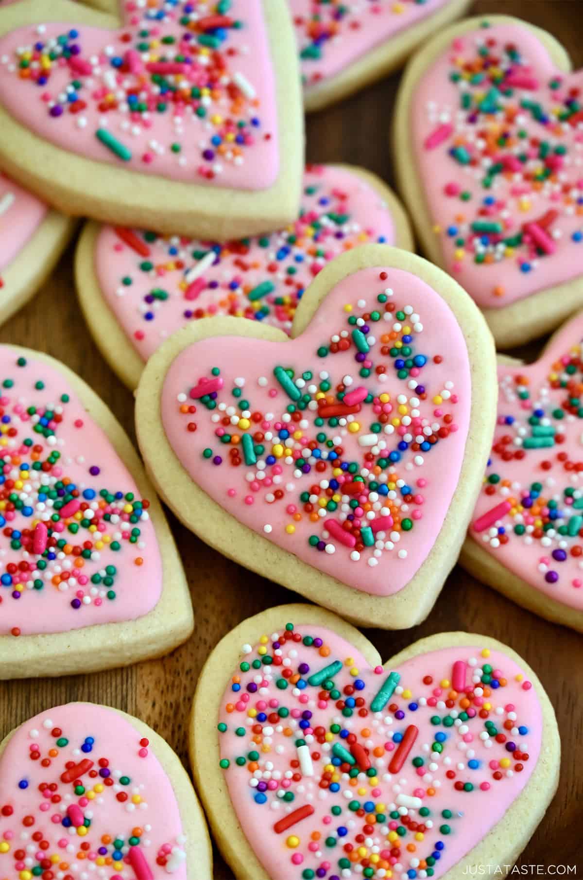 Pink royal icing with sprinkles on heart-shaped sugar cookies.
