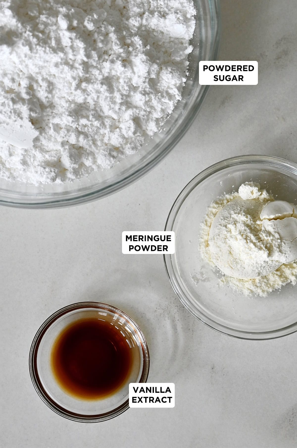 Ingredients to make royal icing, including meringue powder, powdered sugar and vanilla extract.