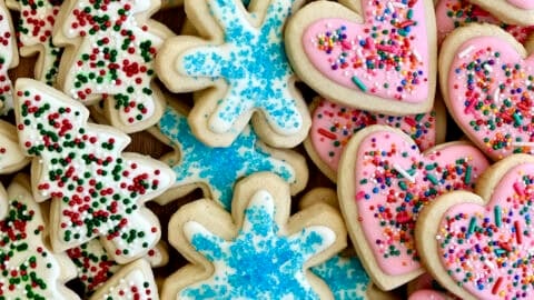 Sugar cookies with royal icing and sprinkles on a plate.