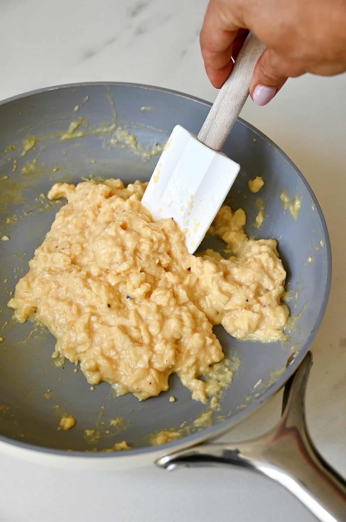 Soft scrambled eggs nearly finished cooking in a nonstick skillet, glossy and custardy with small curds.