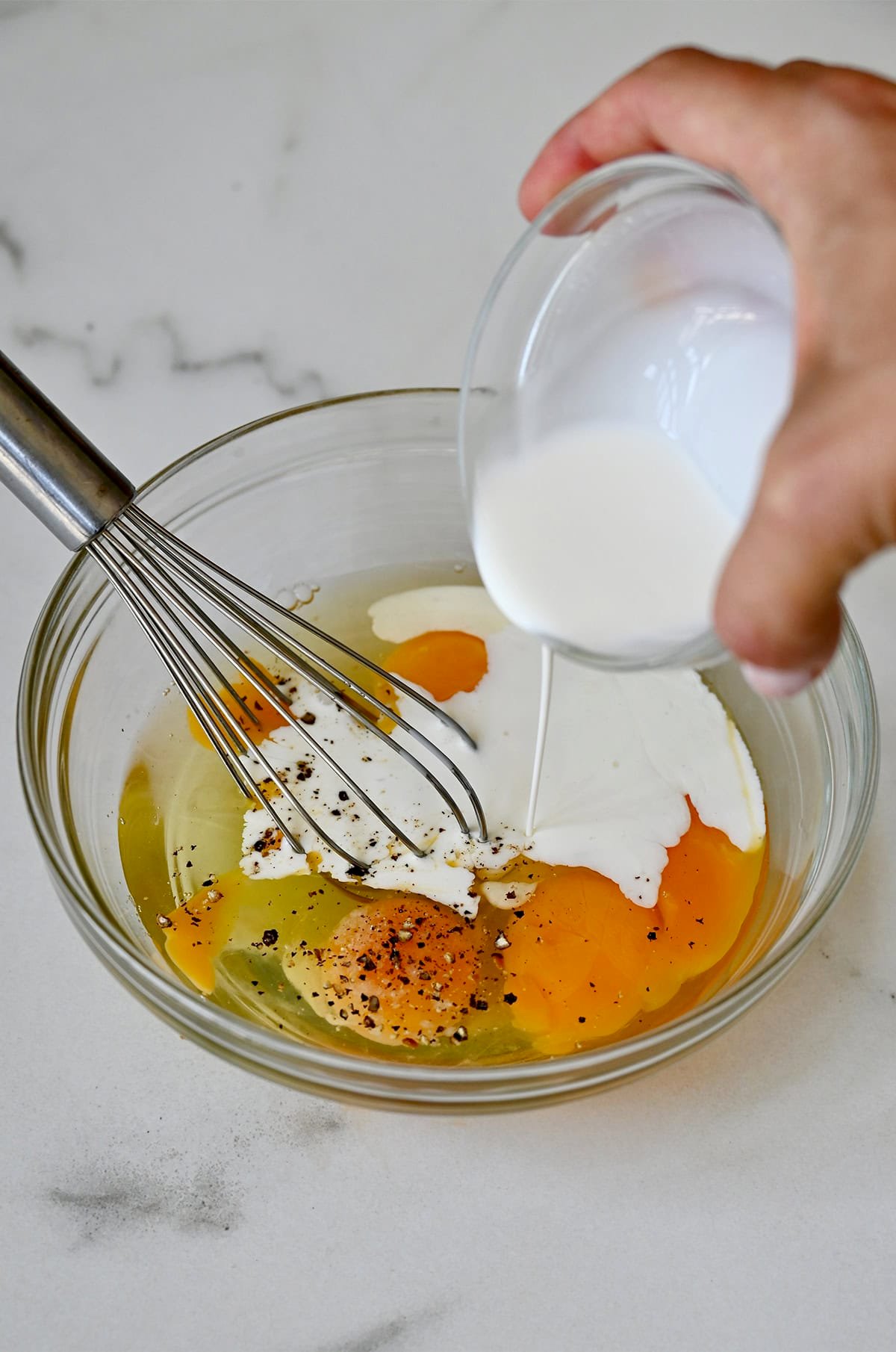 Whisking eggs with milk in a bowl.