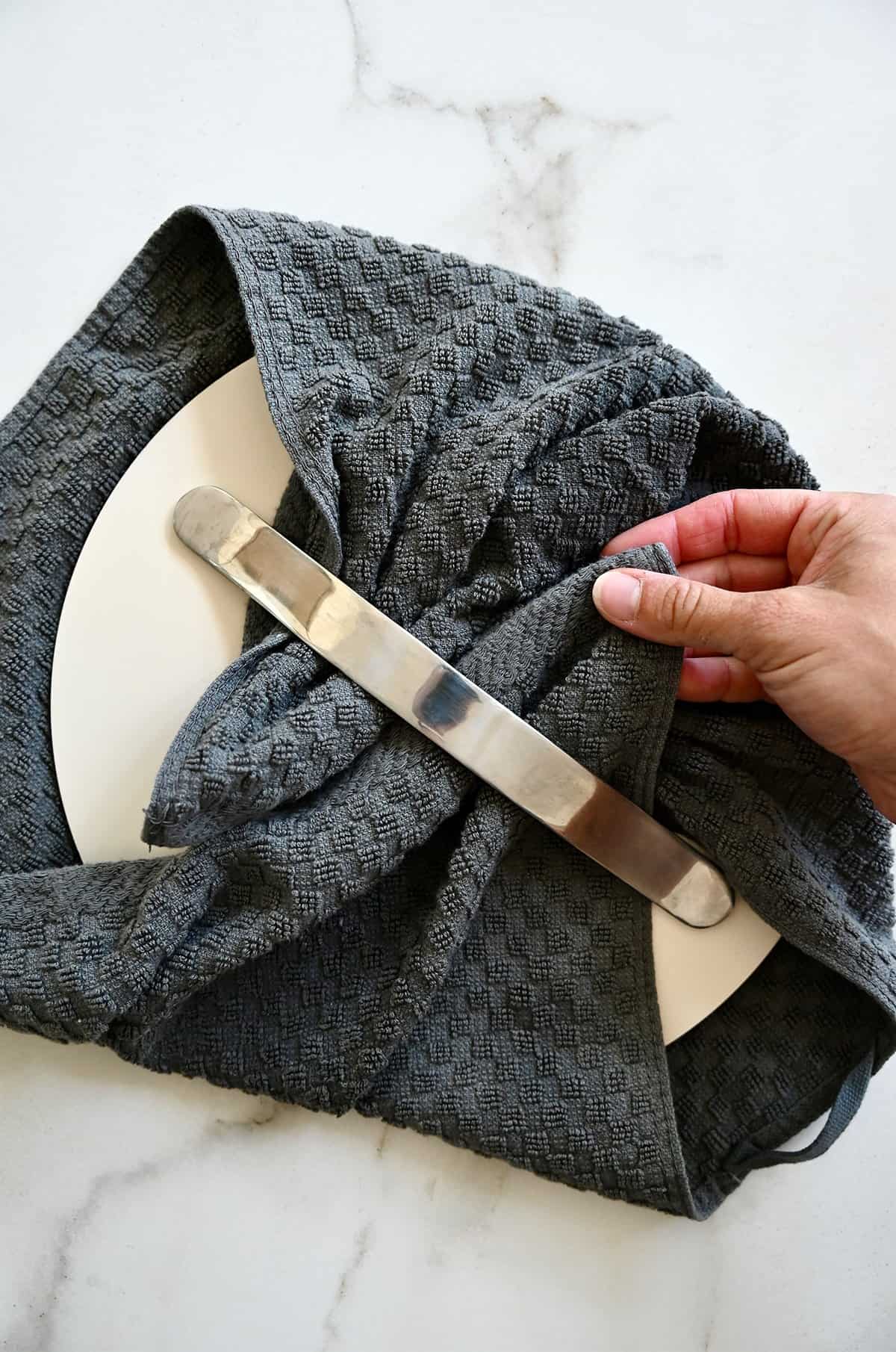 How to wrap a towel around the lid of a saucepan.