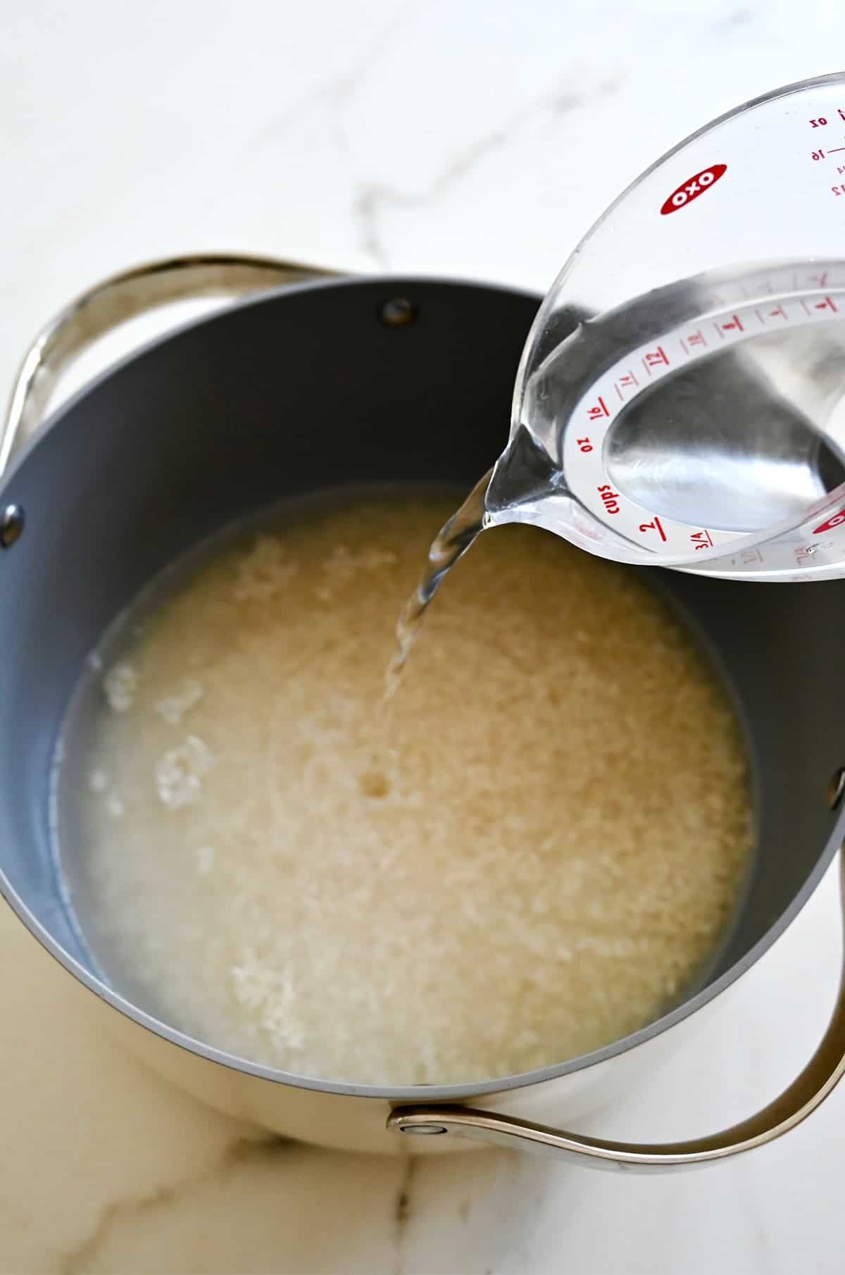 Adding water to a pot with white rice.