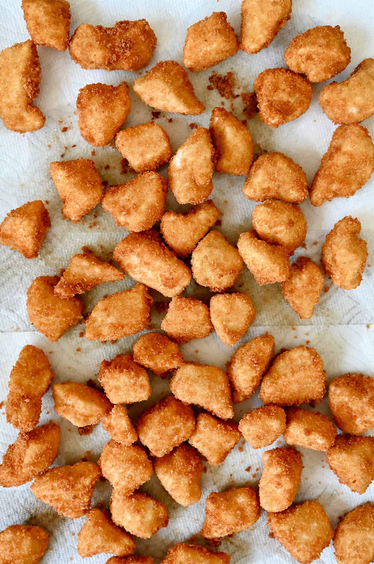 Golden brown fried breaded chicken pieces on a paper towel-lined plate.