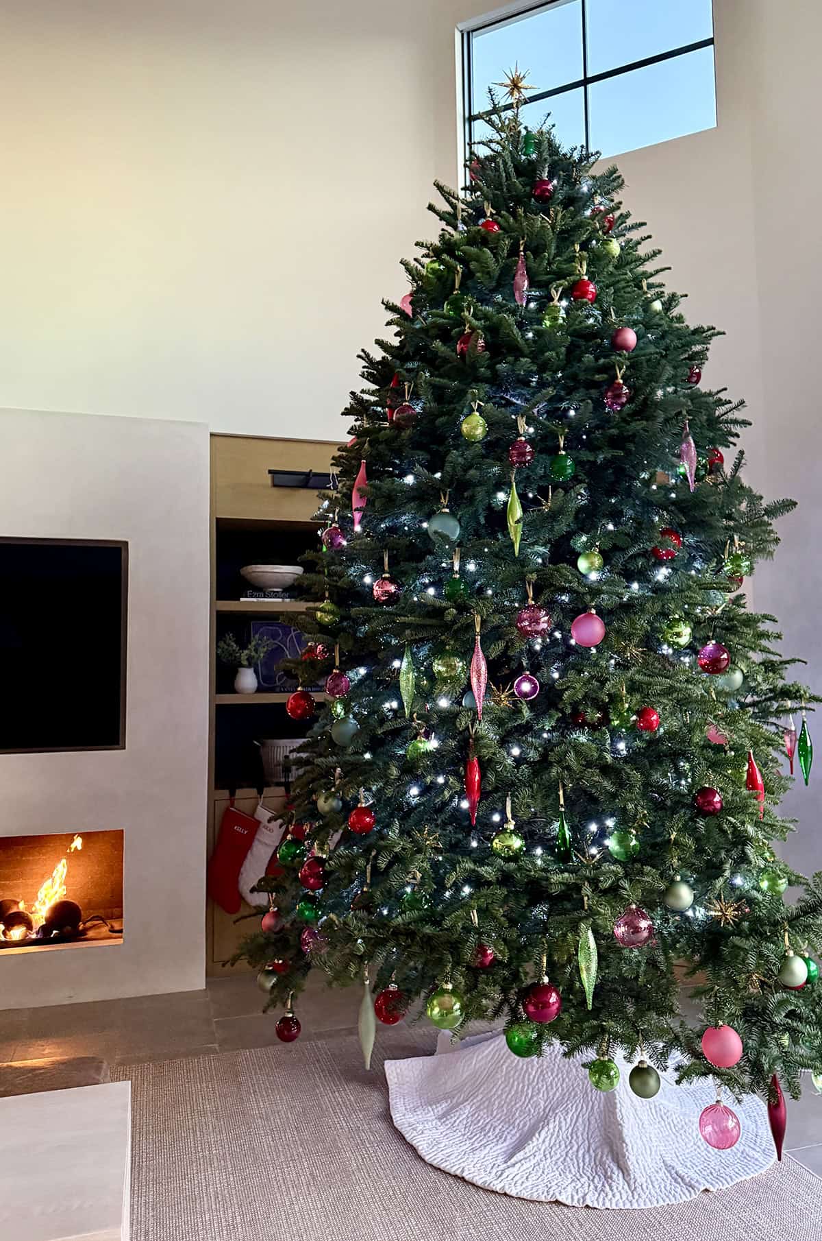 A Christmas tree decorated with ornaments next to a fire