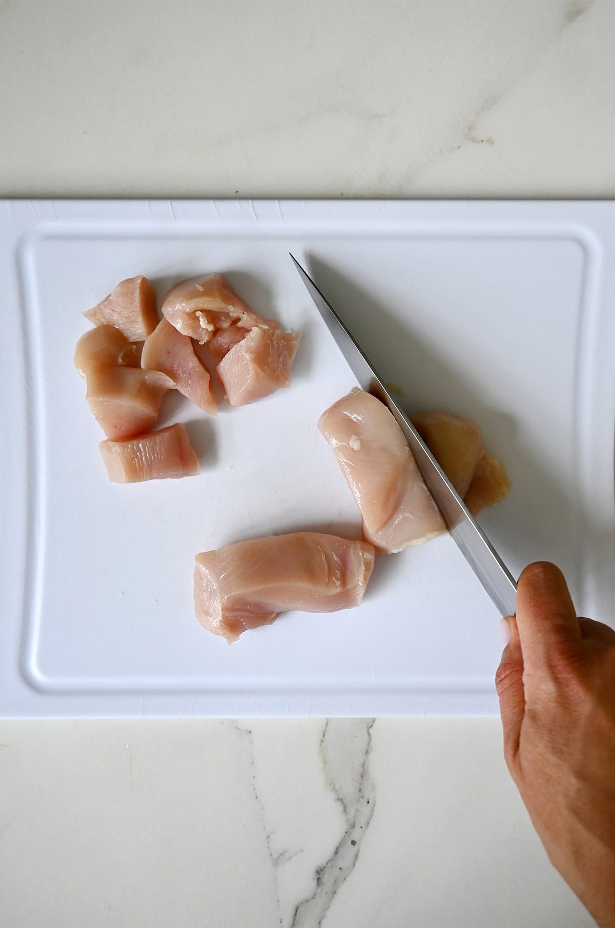 Cutting chicken breasts into 1-inch pieces.