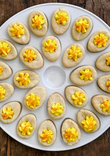 Soft sugar cookie cups decorated to look like deviled eggs, filled with buttercream frosting and finished with orange sanding sugar.
