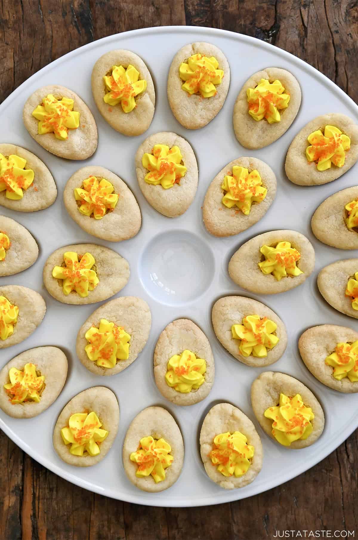 Soft sugar cookie cups decorated to look like deviled eggs, filled with buttercream frosting and finished with orange sanding sugar.