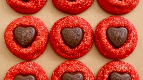 Valentine's Day cookies starring chewy peanut butter cookies rolled in red sanding sugar, then finished with a Reese’s peanut butter heart pressed right into the center.