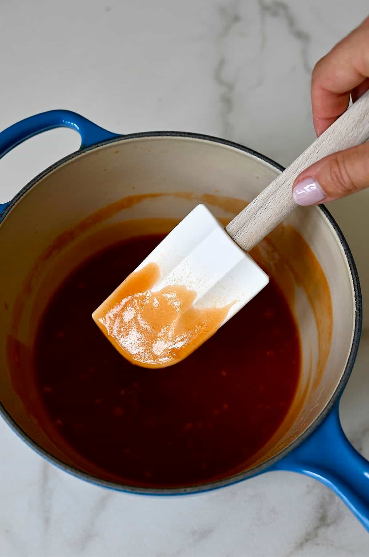 Thickened sweet and sour sauce coating a spatula and in a saucepan.
