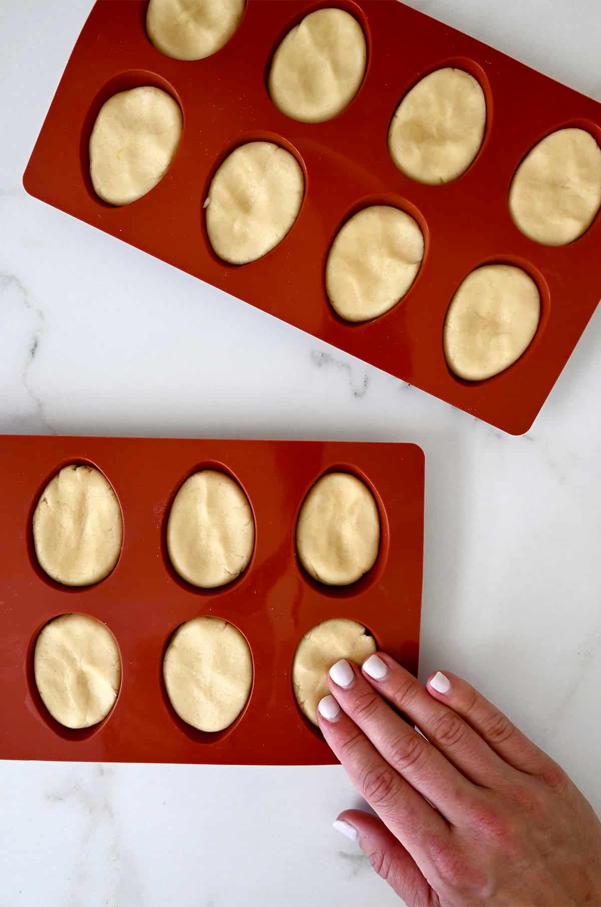 Sugar cookie dough pressed into egg-shaped silicone molds before baking.