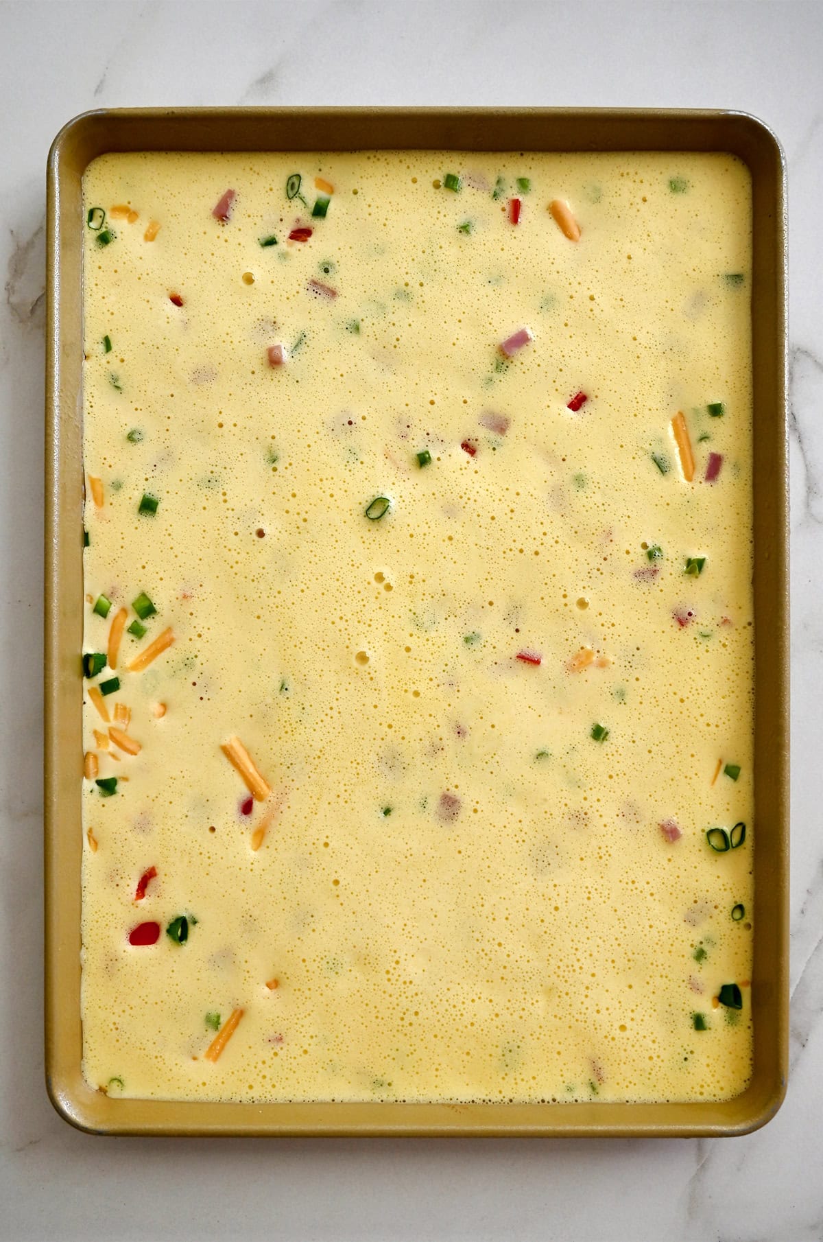 A sheet pan containing a whipped egg and cottage cheese mixture.