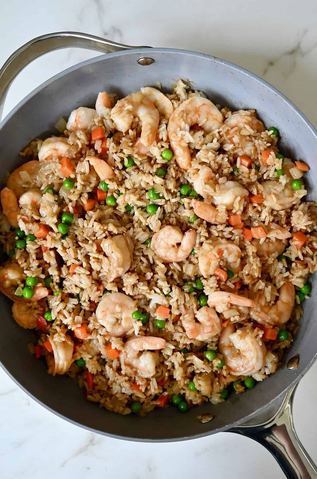 Shrimp fried rice with peas and carrots in a large skillet.