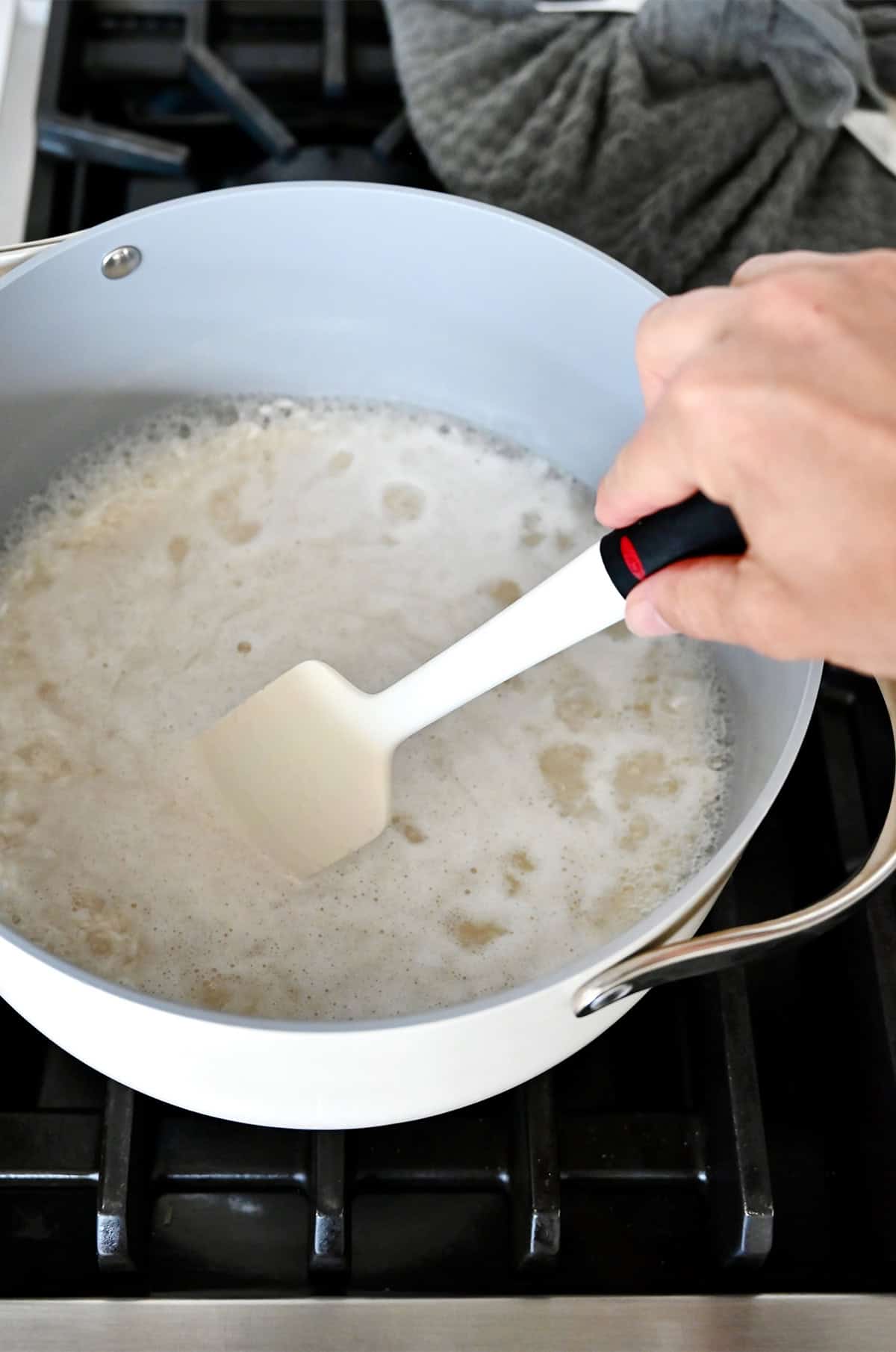Stirring rice and water in a pot to make sure the rice is evenly distributed.