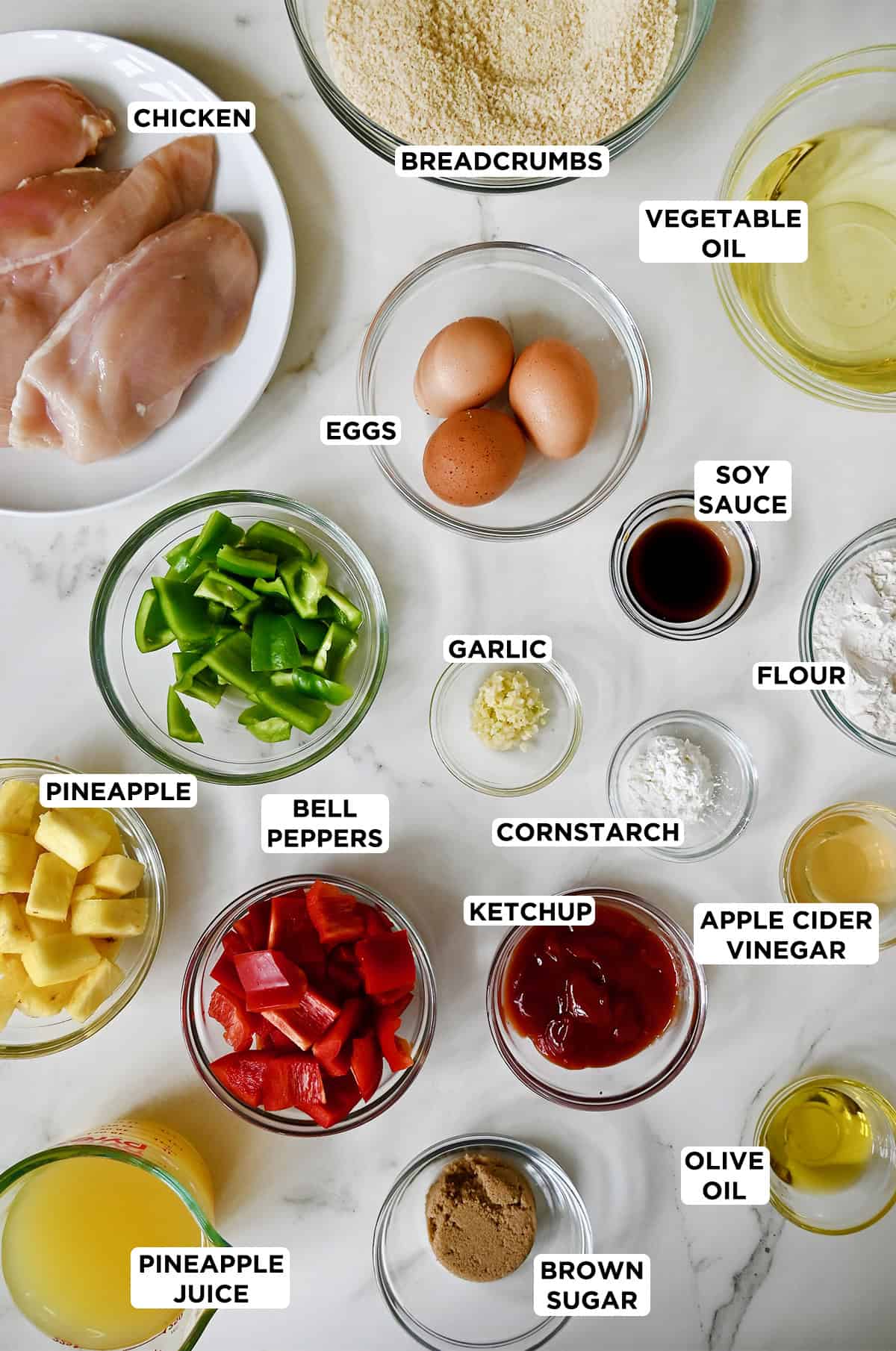 Ingredients to make sweet and sour chicken in various sizes of glass bowls.