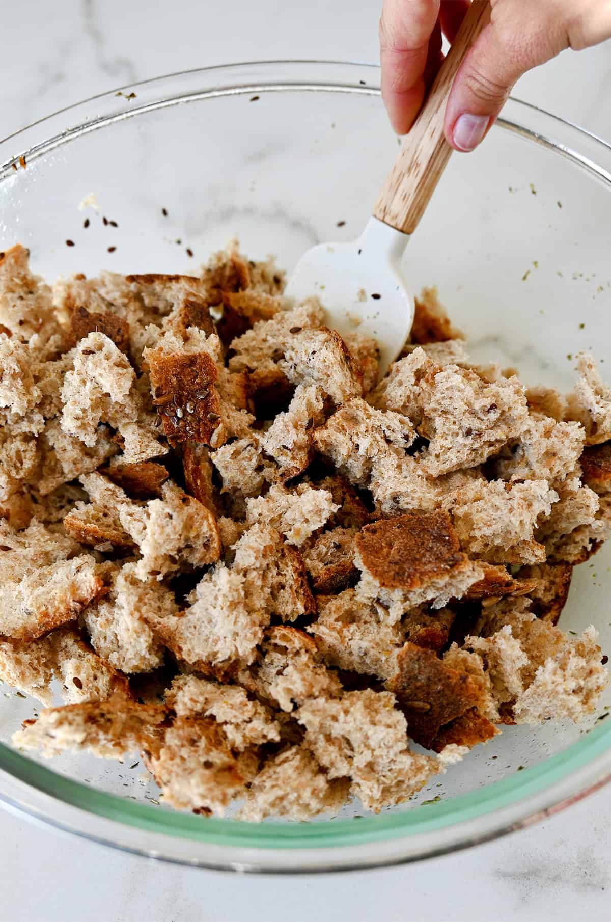 Pieces of bread coated in olive oil and spices in a large bowl.