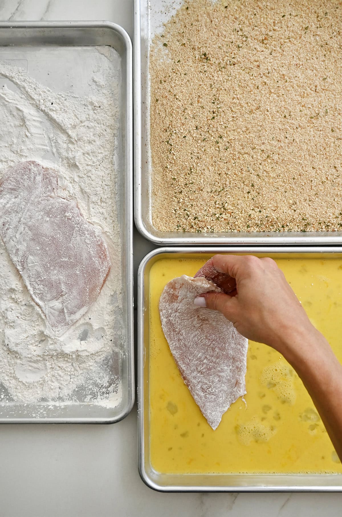 Breading station for coating chicken cutlets in egg, flour and breadcrumbs.