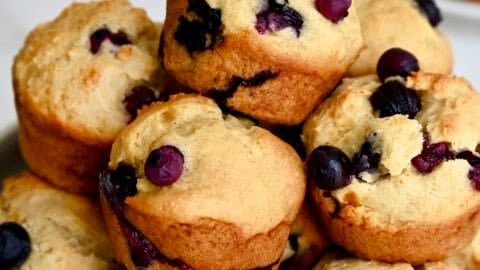 Blueberry muffins made with cottage cheese piled high on a white plate.