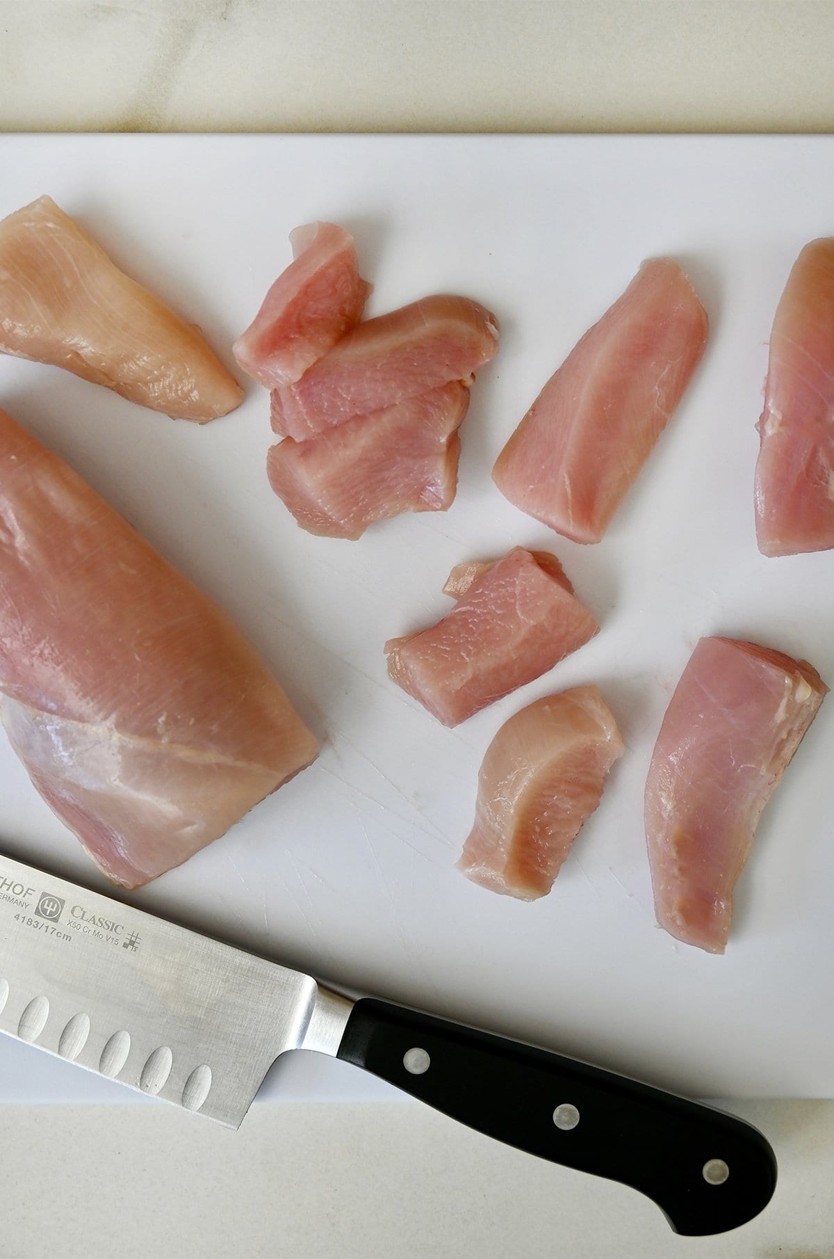 Cutting chicken breasts into nuggets.