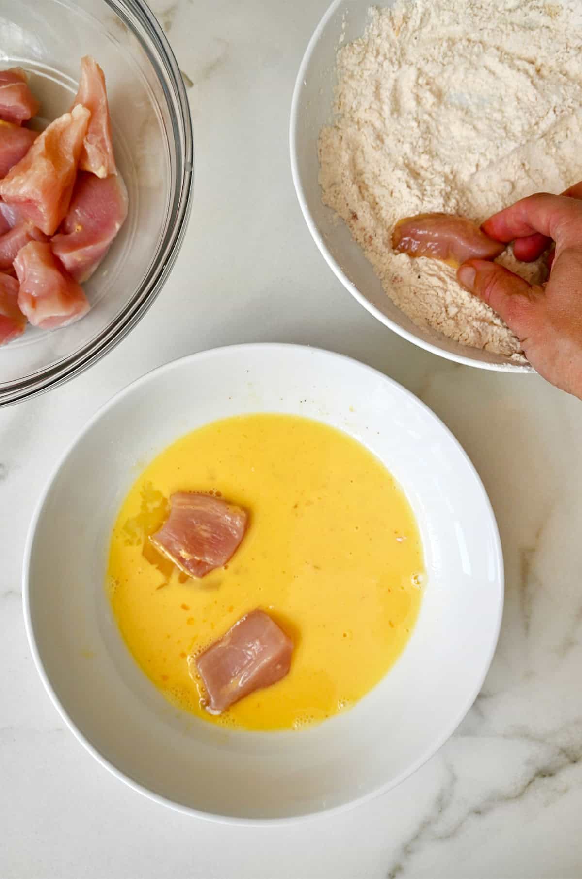 Dredging chicken bites in egg and flour to give it a light batter for frying.