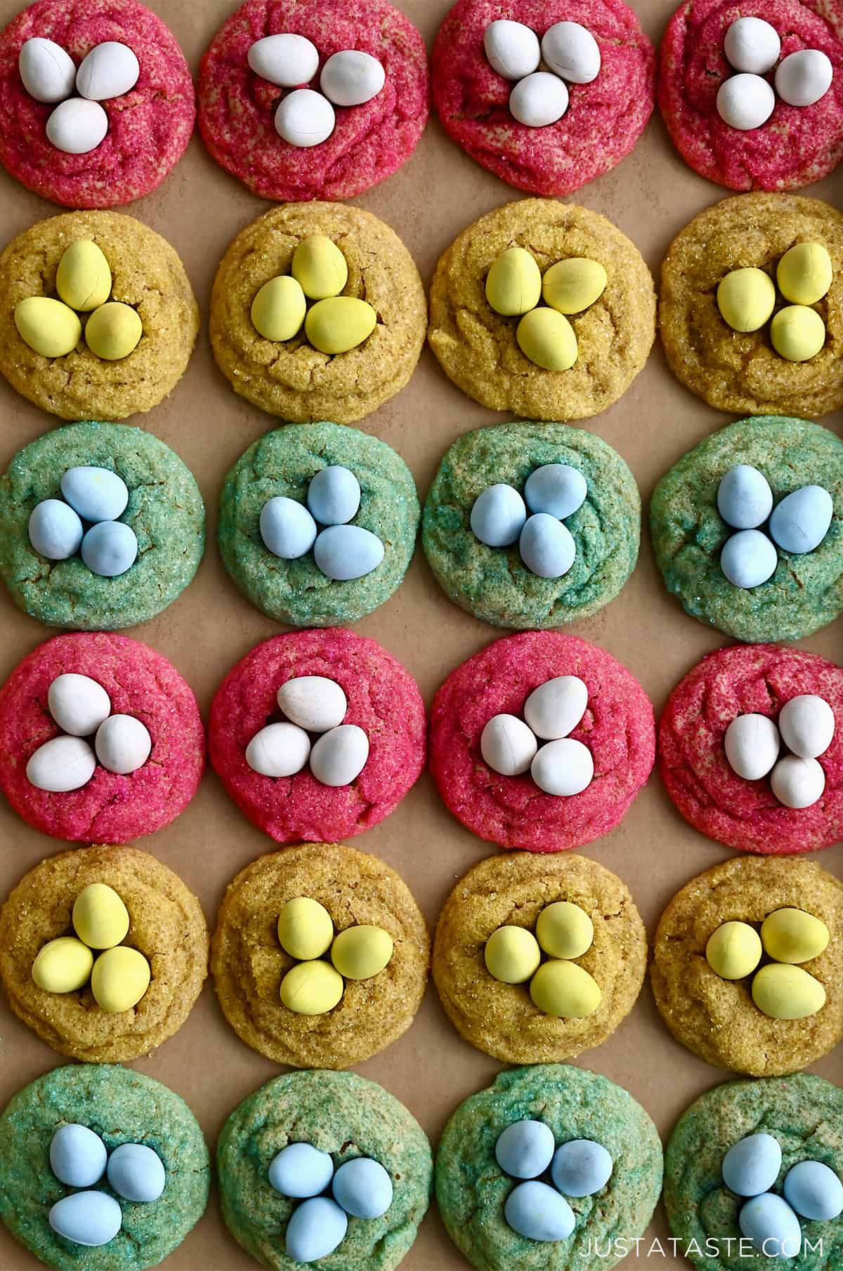 Peanut butter Cadbury Egg cookies rolled in pink, blue and yellow sanding sugar and topped with crunchy Mini Cadbury Eggs.