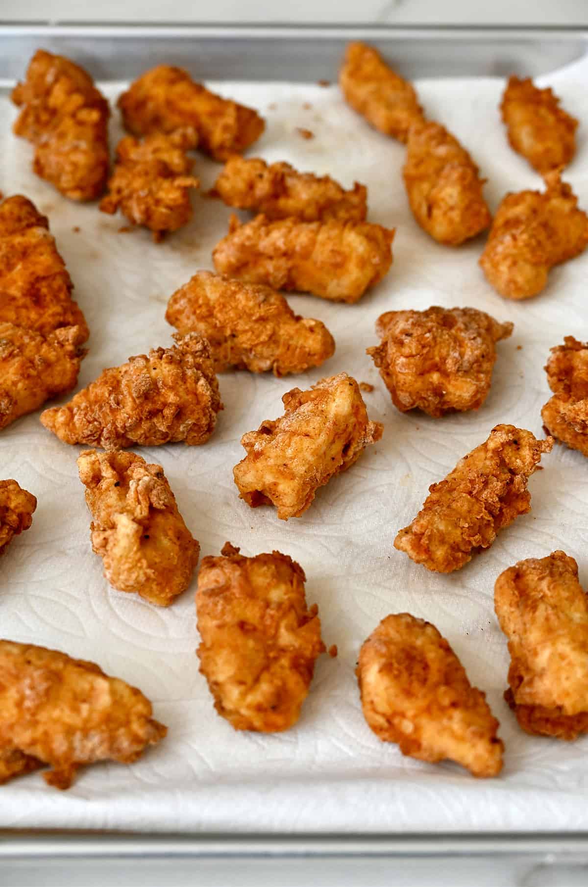 Fried chicken pieces on a paper towel-lined plate.