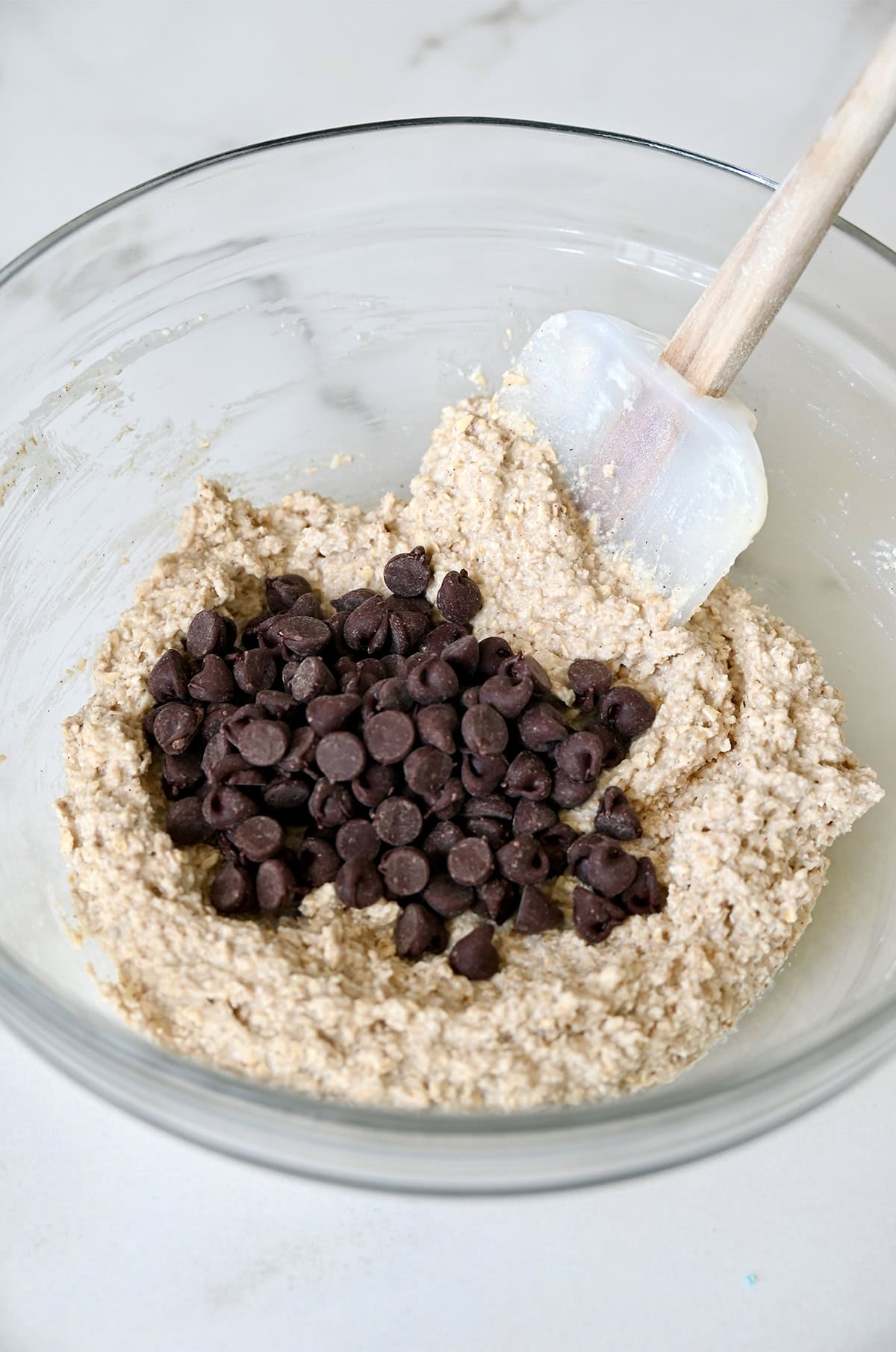 Folding chocolate chips into a cottage cheese and oat flour mixture to make edible cookie dough.