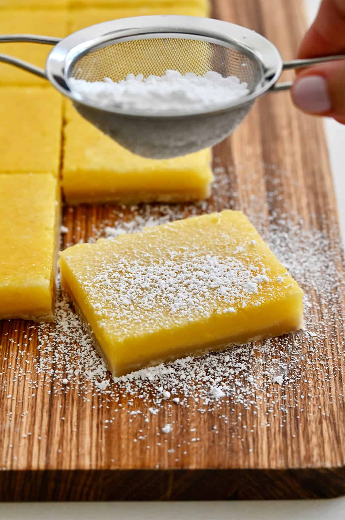 Dusting lemon bars with powdered sugar.