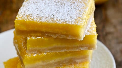 Lemon bars stacked five high and dusted with powdered sugar.