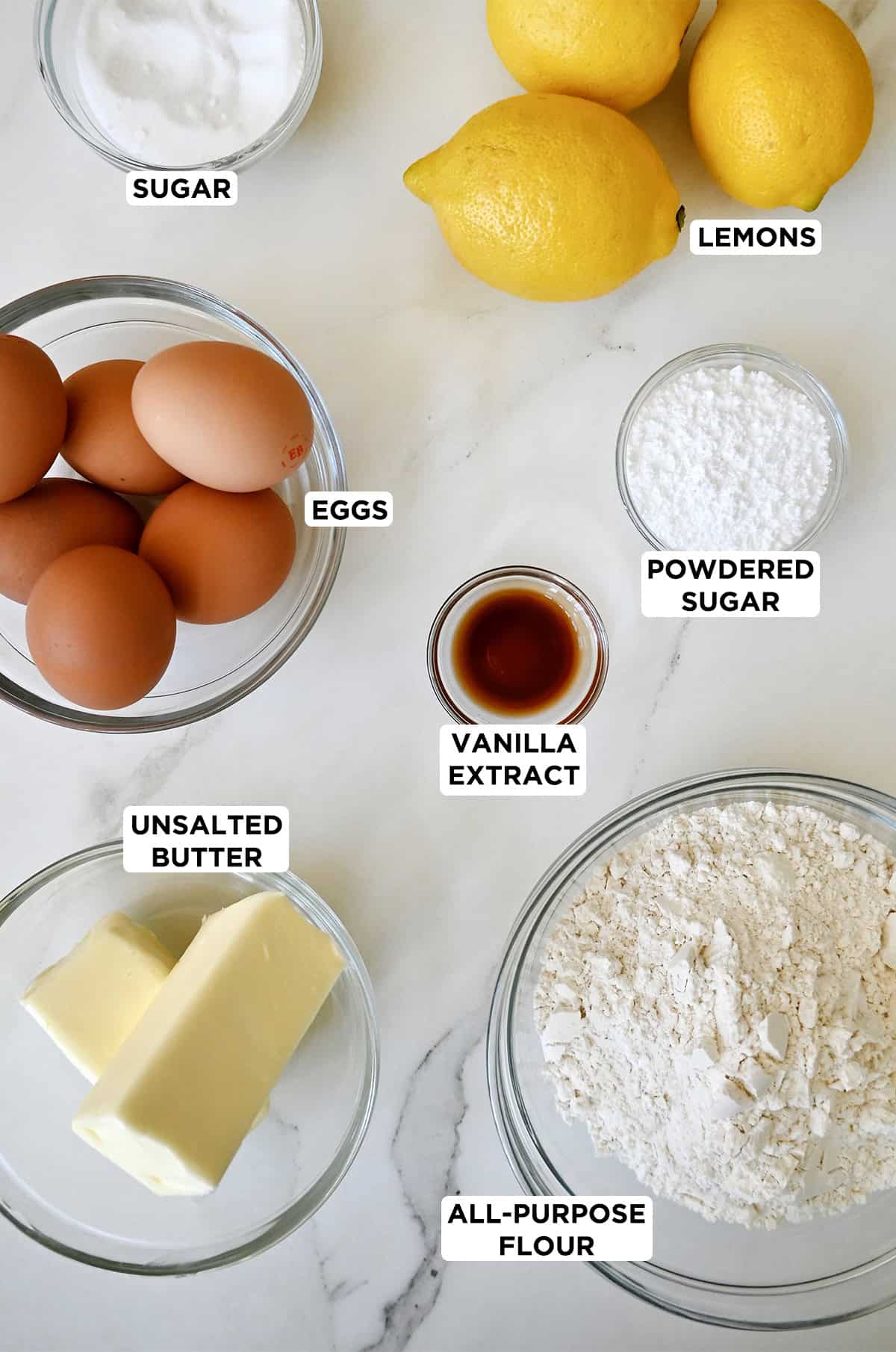 The six ingredients needed to make lemon bars, plus the optional addition of powdered sugar for dusting the bars.