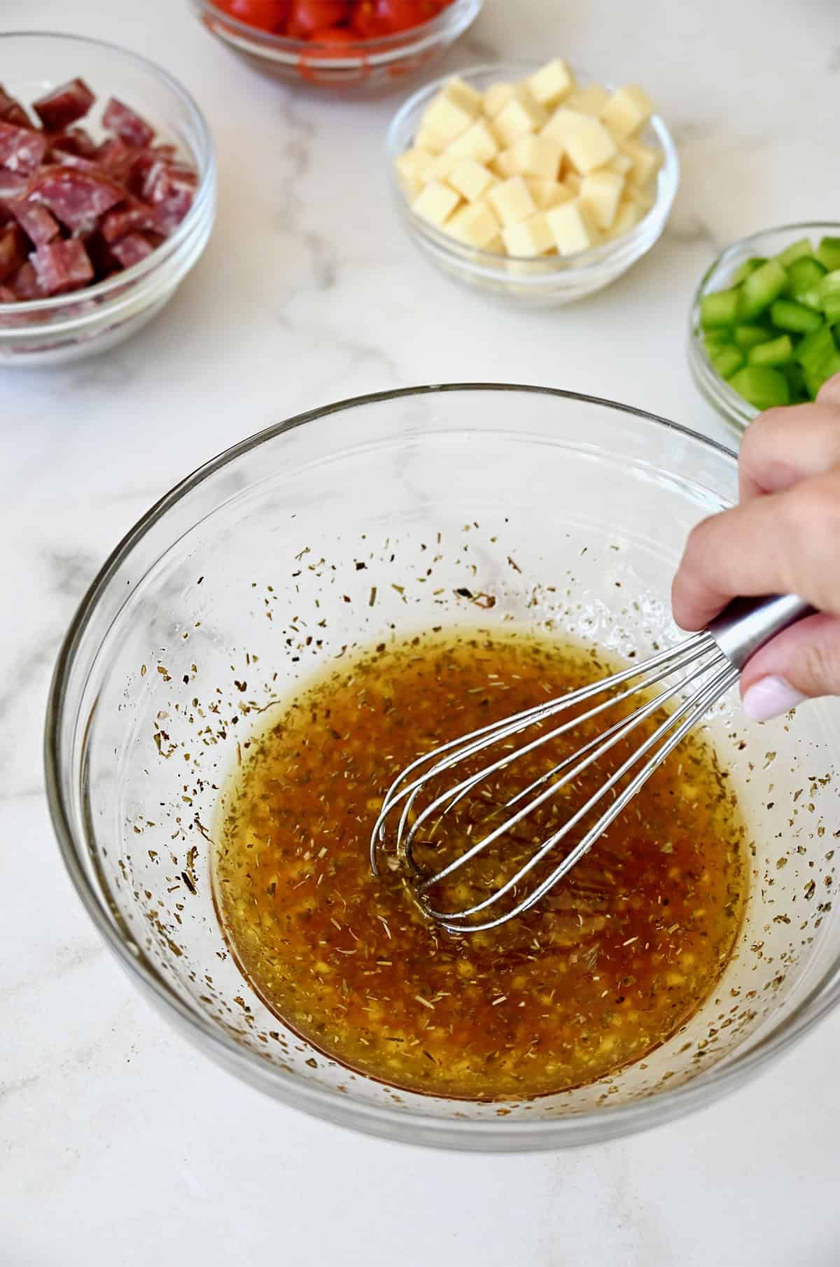 Whisking together a homemade Italian dressing in a medium bowl.