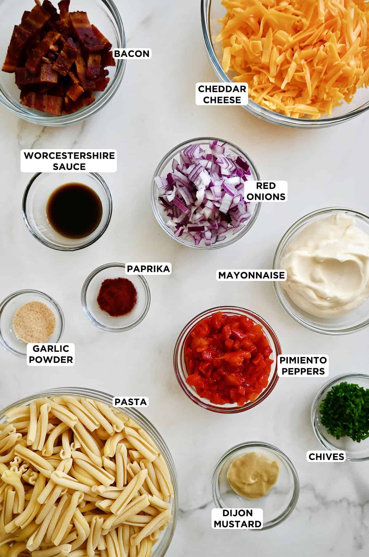 Ingredients for pimento cheese pasta salad in various-sized glass bowls.