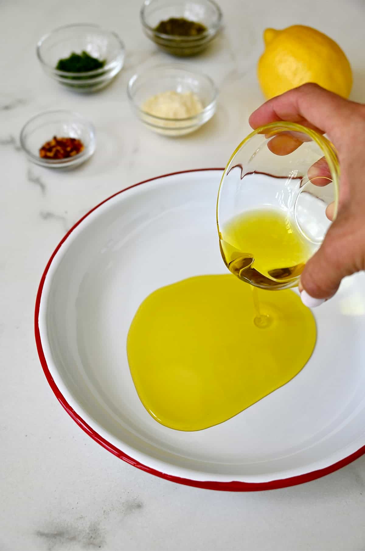 Adding extra-virgin olive oil to a shallow plate with a lip.
