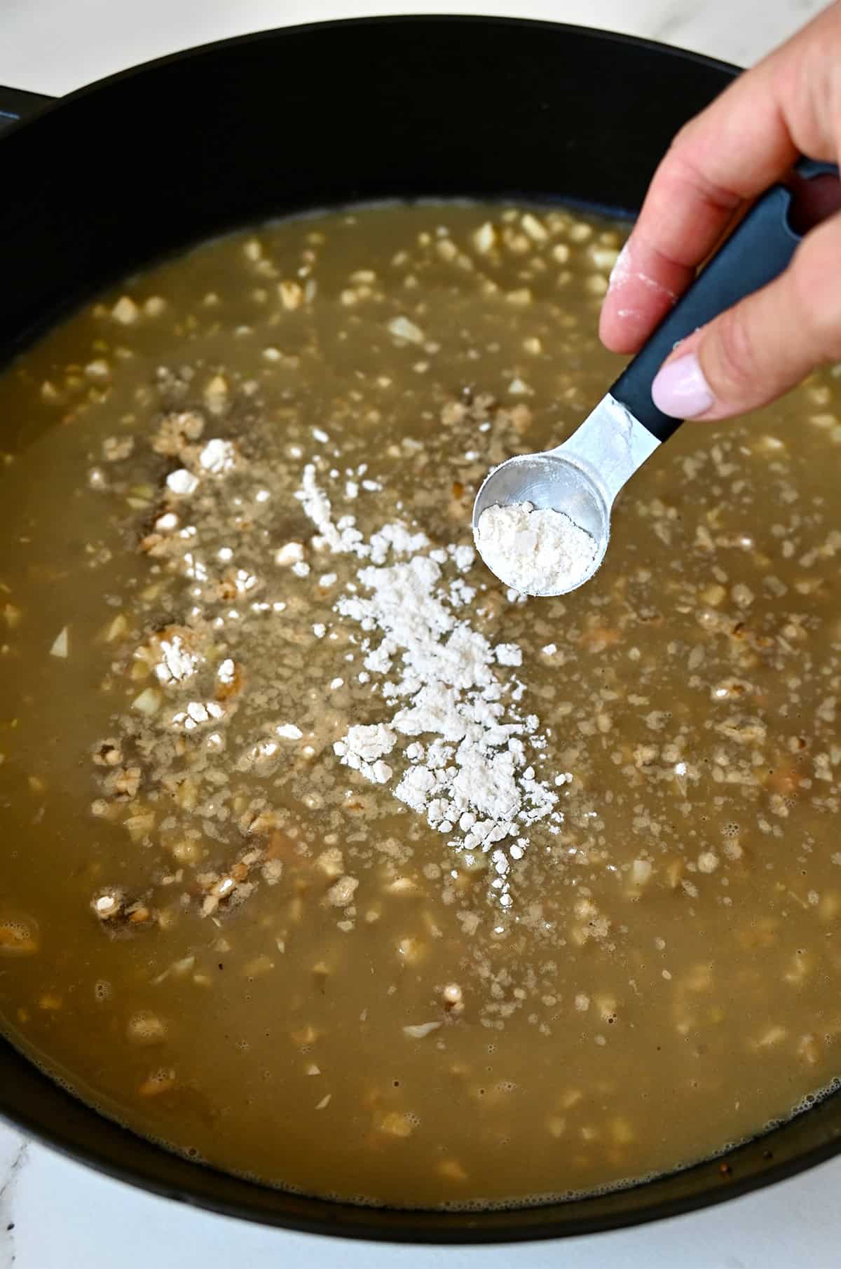 Thickening a garlic butter pan sauce with flour.