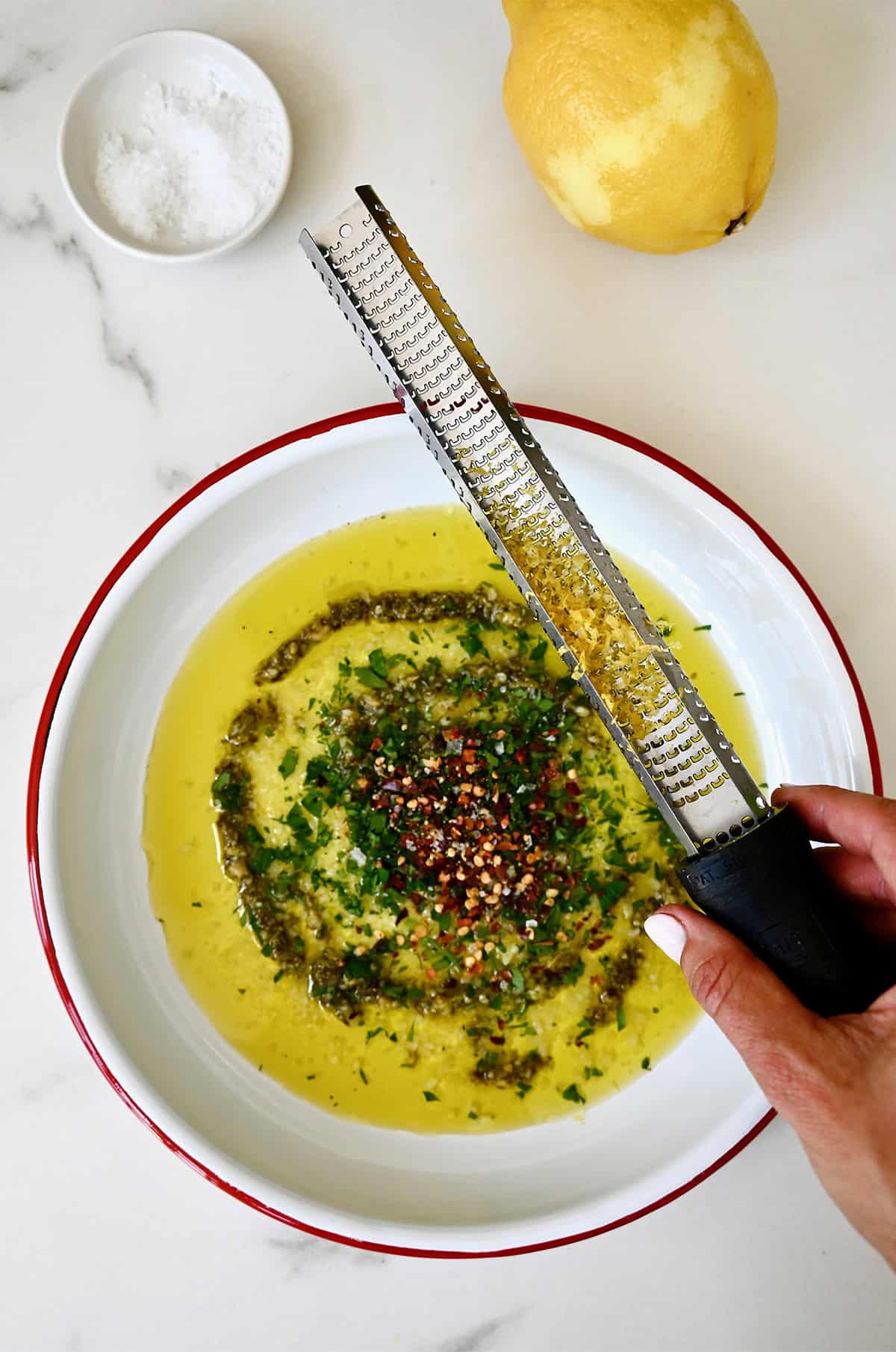 Zesting a lemon over a plate of Italian bread dipping oil.
