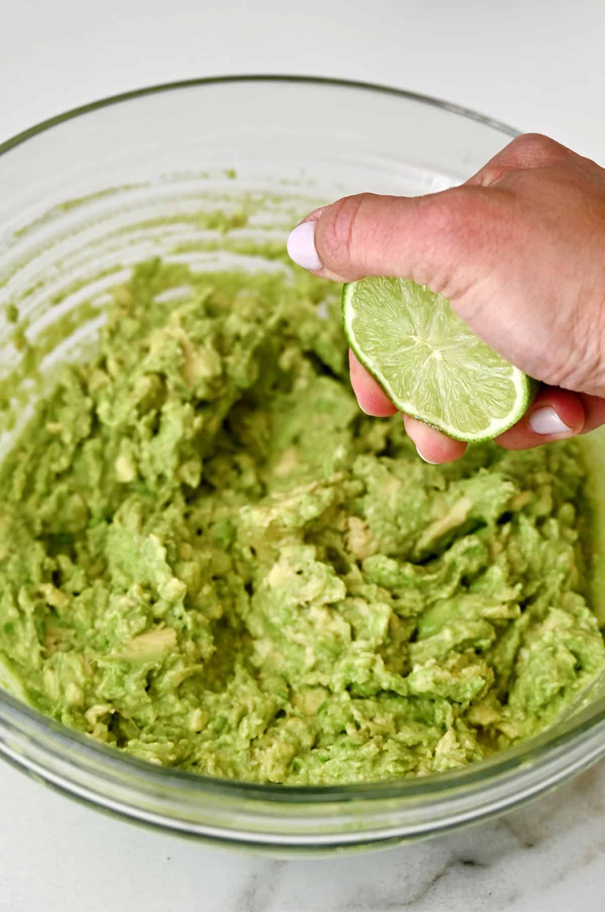 Squeezing fresh lime juice into a bowl with homemade guacamole.