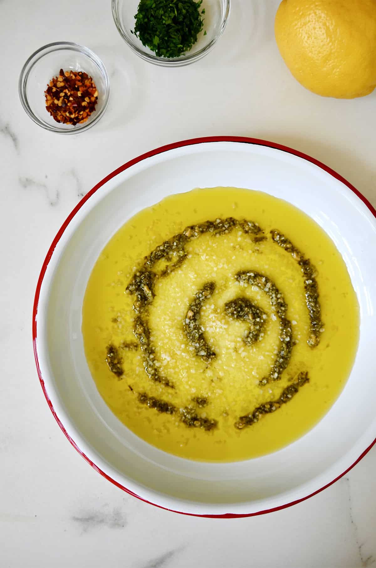 A shallow plate with olive oil, pesto and grated Parmesan cheese.