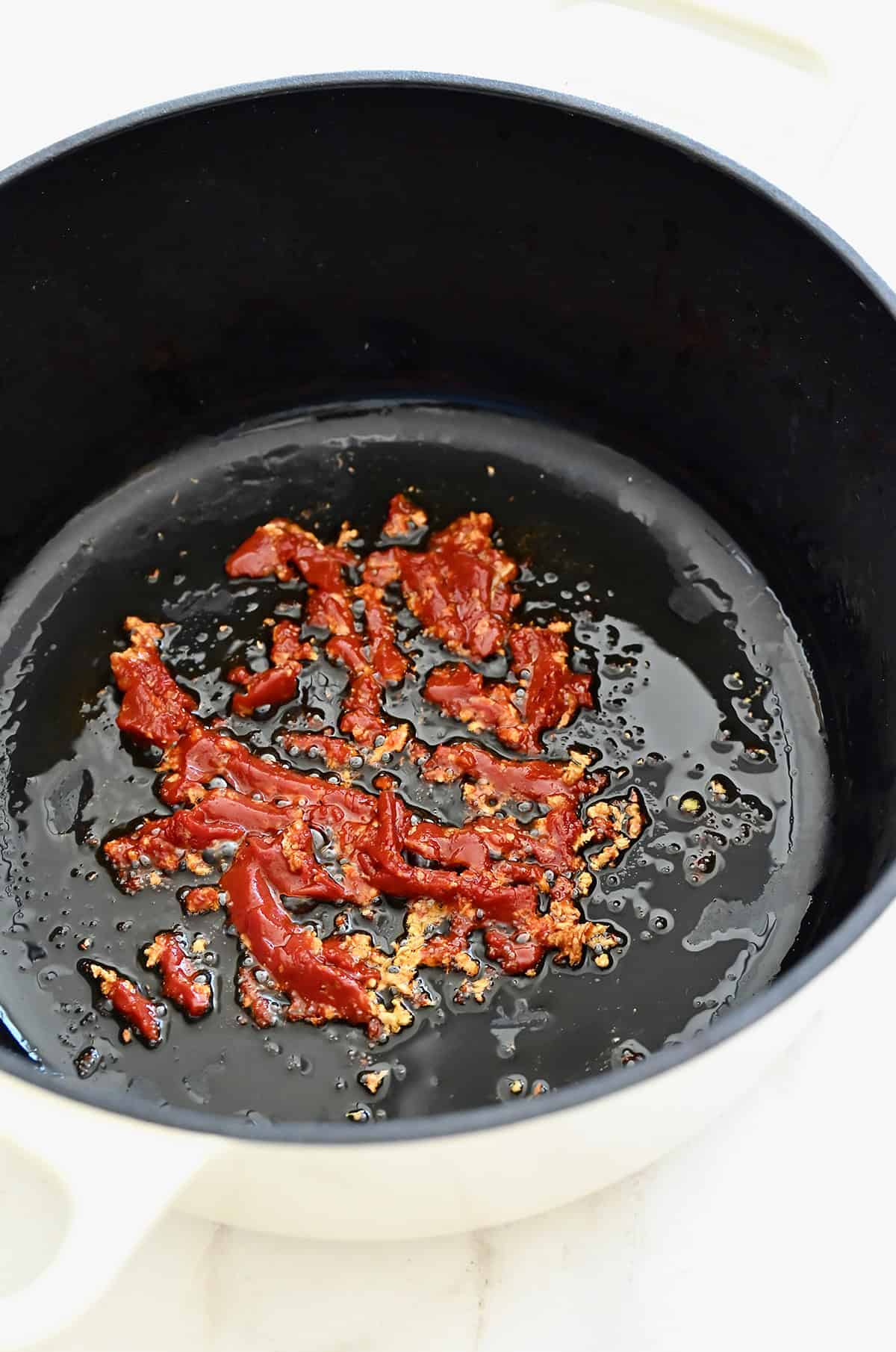 Caramelizing tomato paste in a large pot with saut&eacute;ed garlic.