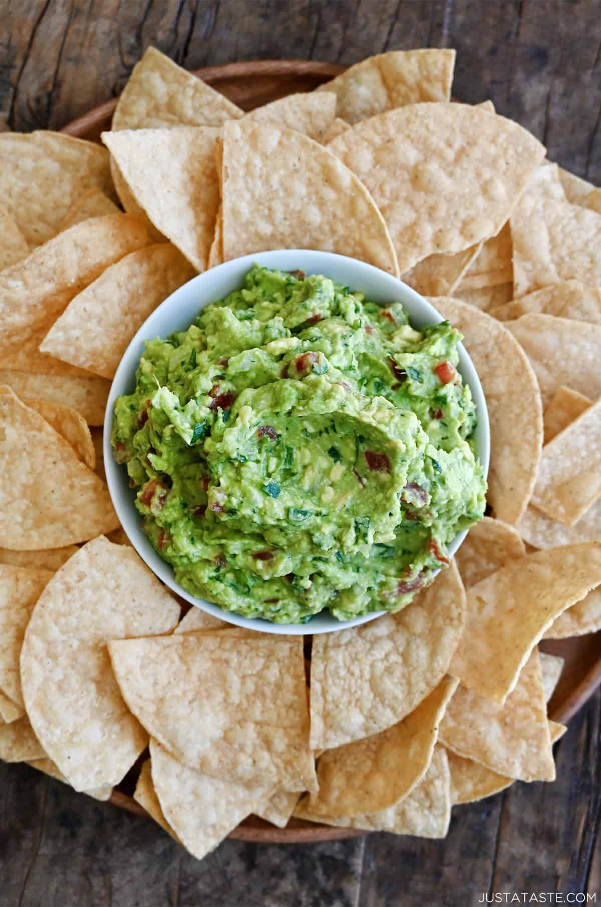 Best guacamole recipe in a bowl on a plate surrounded by chips.