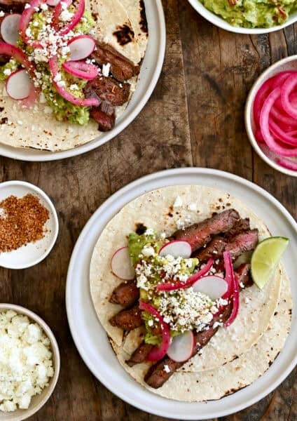 Carne asada tacos topped with pickled onions, cotija cheese and guacamole.