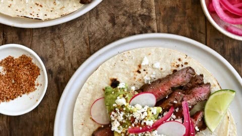 Carne asada tacos topped with pickled onions, cotija cheese and guacamole.