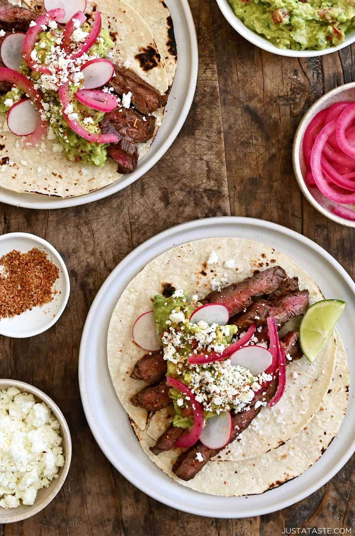 Carne asada tacos topped with pickled onions, cotija cheese and guacamole.