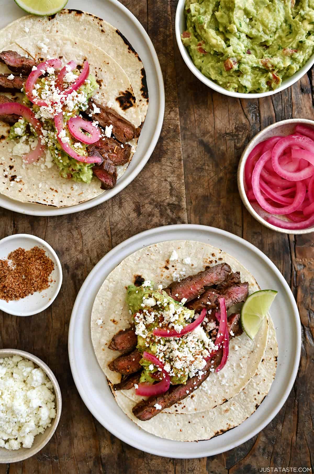 Carne asada tacos with blistered corn tortillas, guacamole, pickled onions and crumbled cotija cheese.