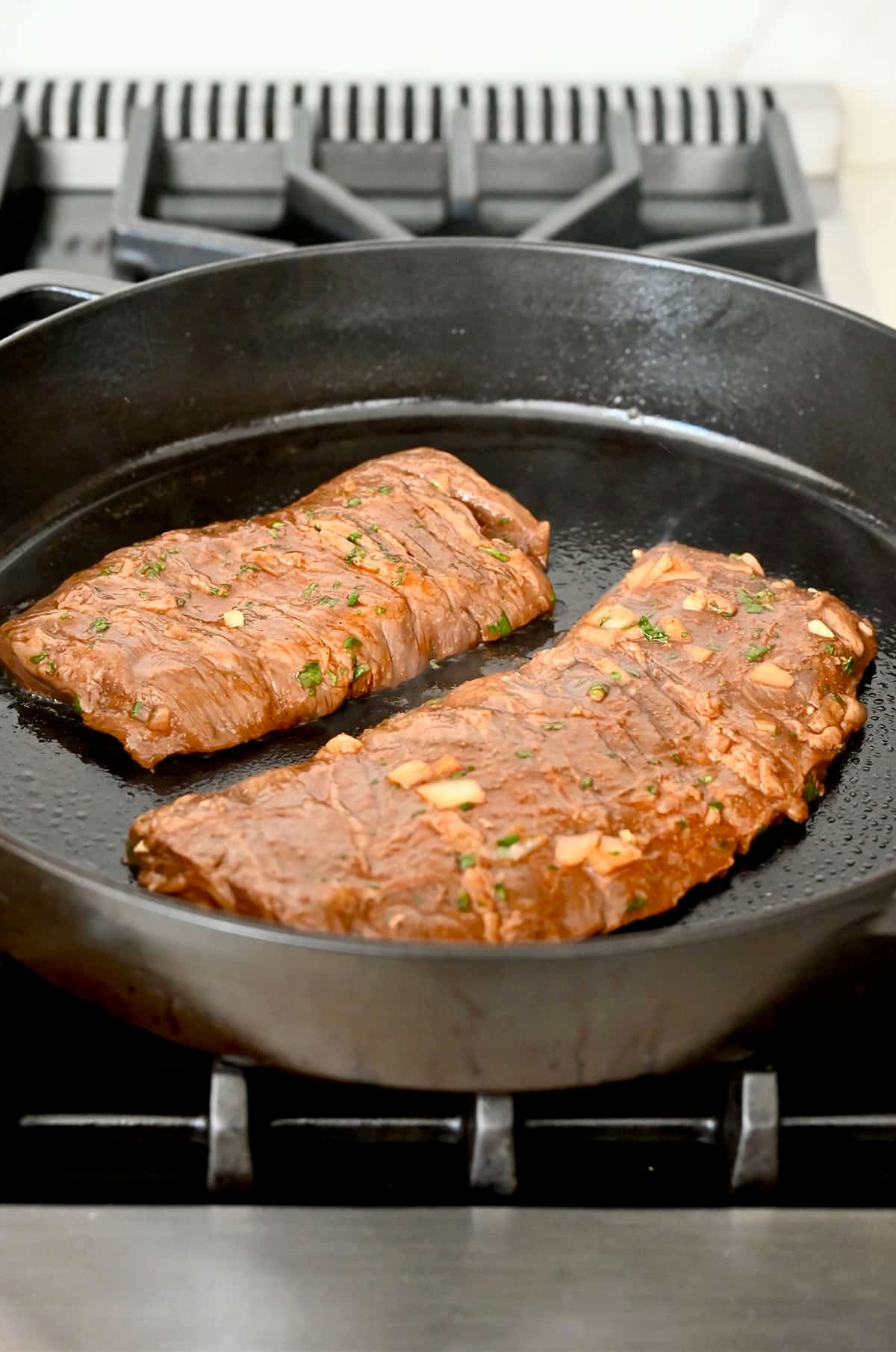 Carne asada cooking on a grill pan.