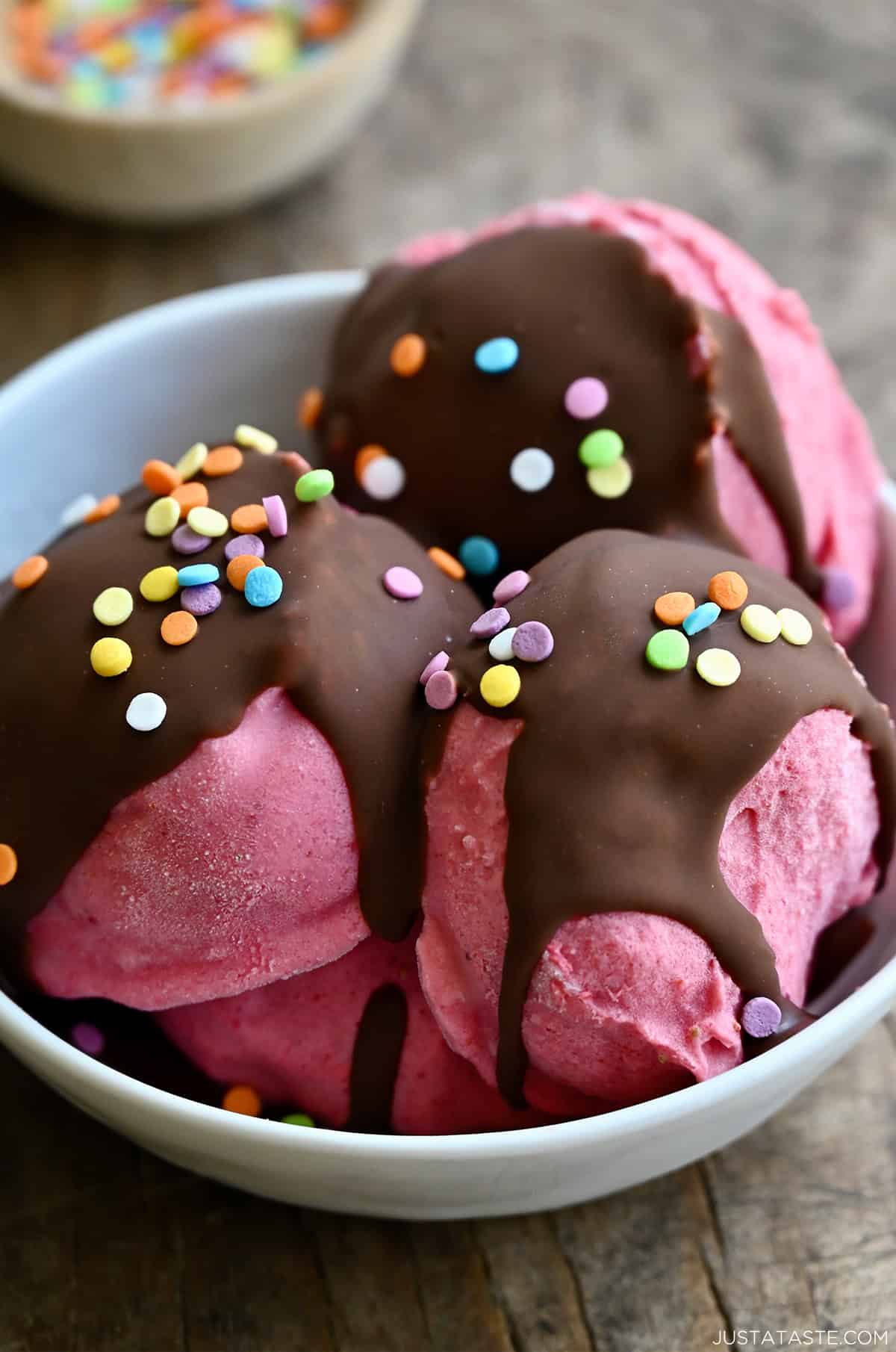 Scoops of cottage cheese ice cream topped with a chocolate magic shell and sprinkles in a bowl.