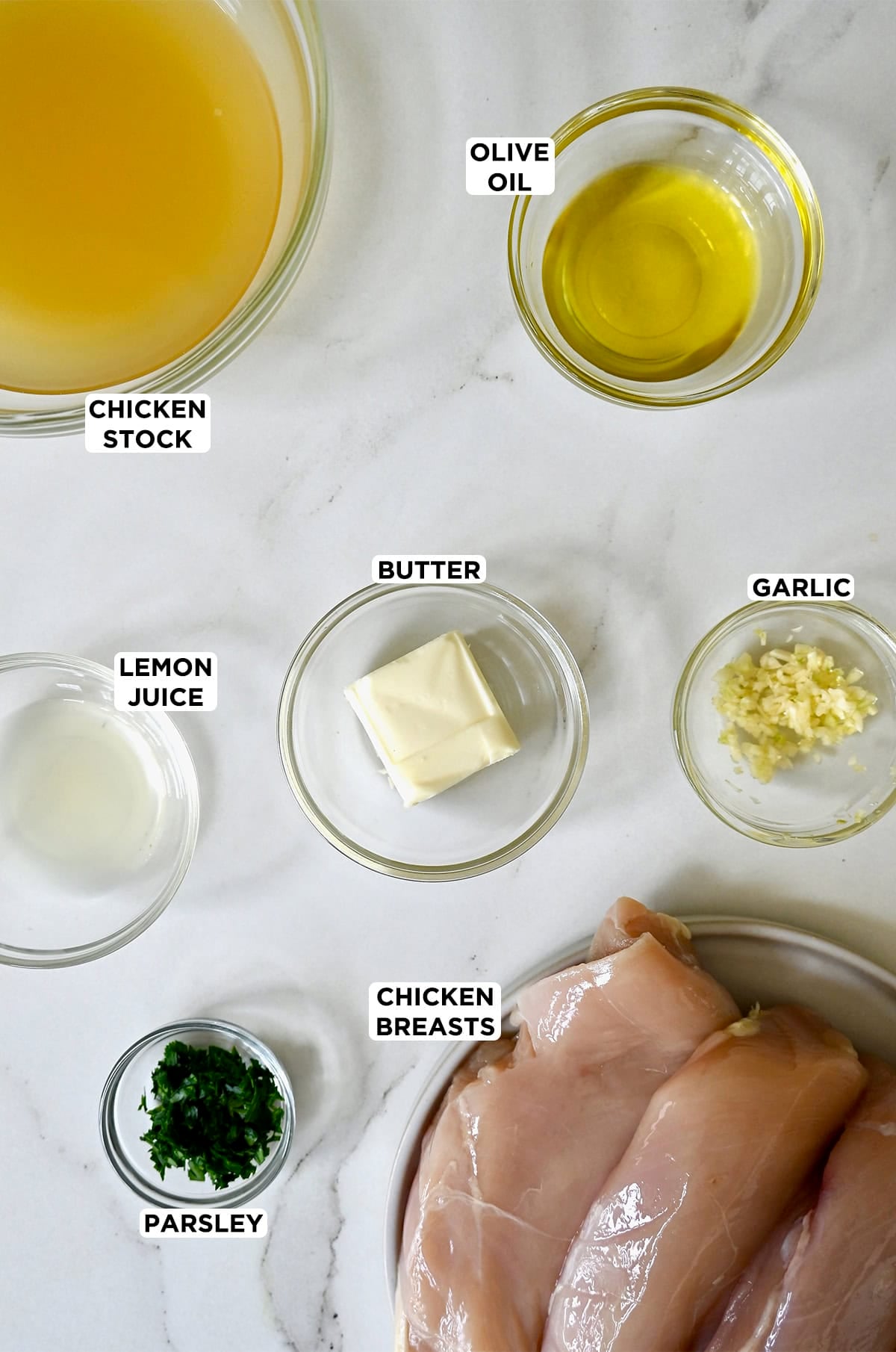 Ingredients to make garlic butter chicken in various sizes of glass bowls.